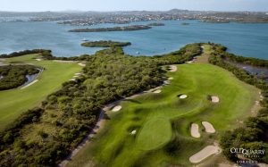 Aerial view of Hole 9 at Old Quarry Golf Course, Curaçao, with a lush green fairway surrounded by bunkers and flanked by stunning ocean and bay views.