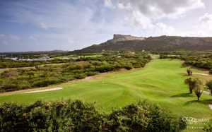 View of Hole 15 at Old Quarry Golf Course Curaçao, with marina to the left, green in the foreground, and the iconic Tafelberg mountain in the background.