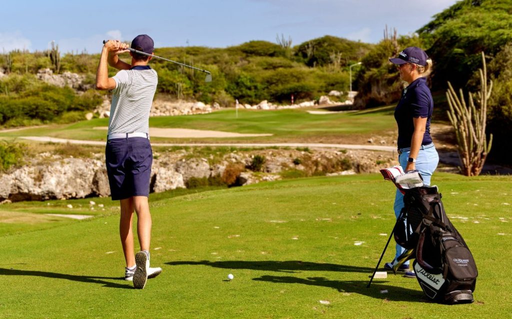 Two golfers at Old Quarry Golf Course teeing off on a scenic green with cactus-lined fairways