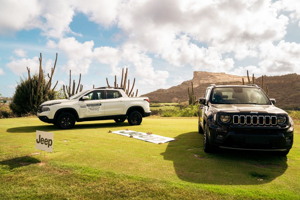 Two Jeep vehicles displayed on the golf course as hole-in-one prizes with scenic hills and blue sky in the background.