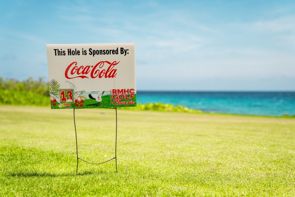 Sponsorship sign for Coca-Cola at RMHC Golf Classic with ocean view at Old Quarry Golf Course Curaçao